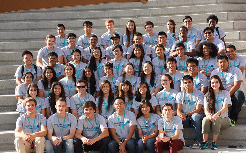 Students wearing grey shirts sitting on steps for photo