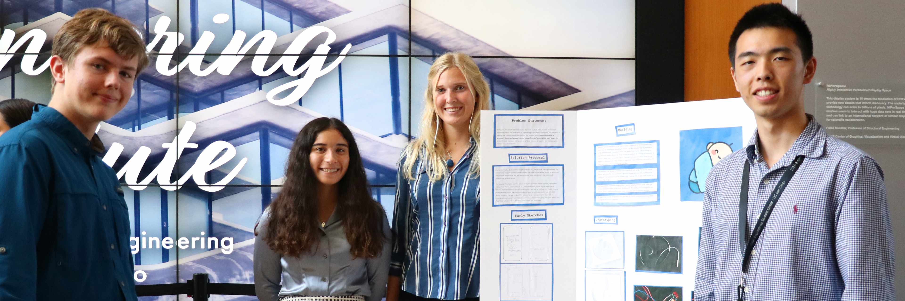 Four students standing next to poster